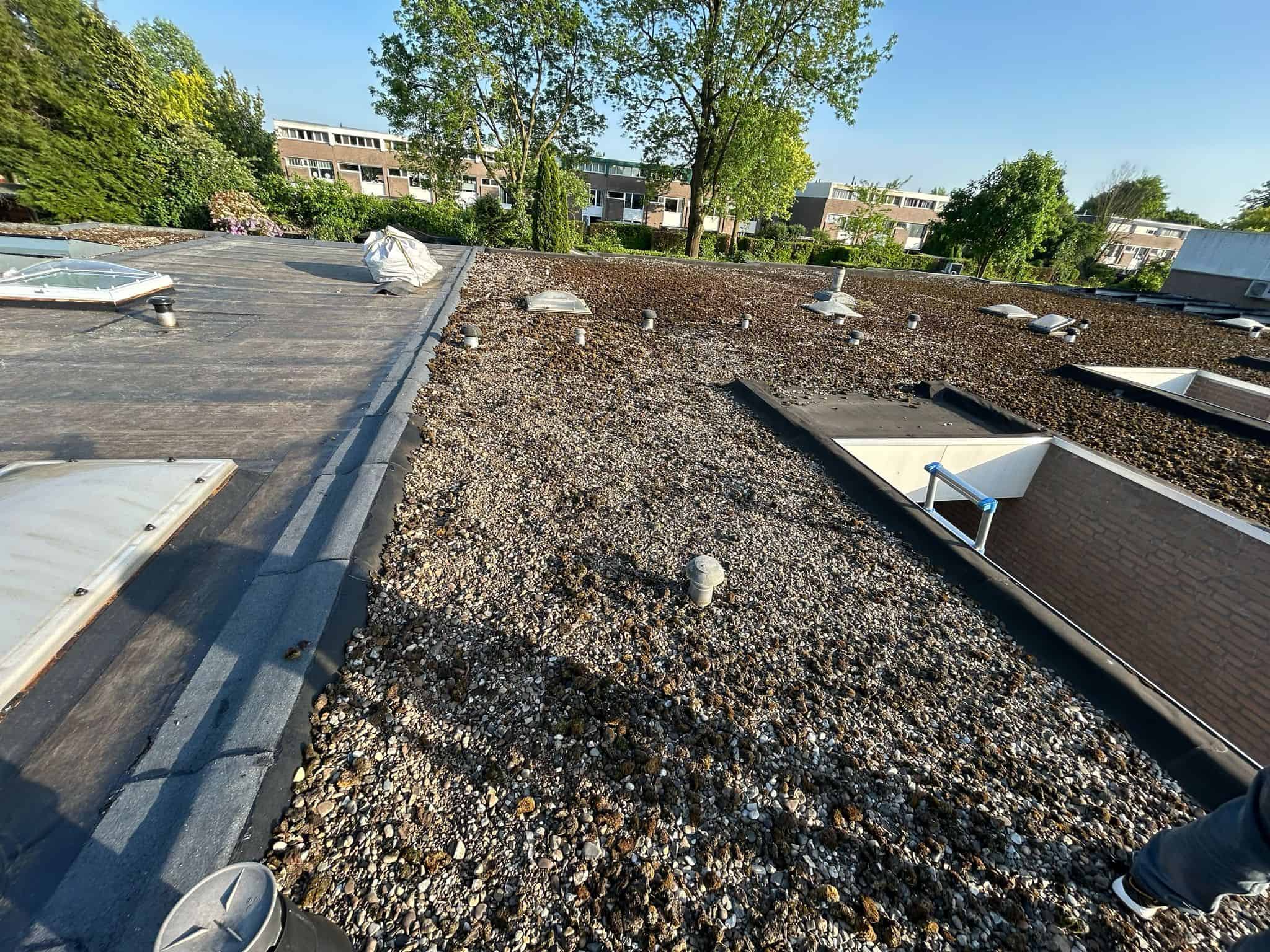 Grindbedekking op plat dak met lichtkoepels en ventilatiepijpen