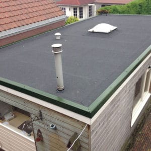 Zwart bitumen plat dak met groene rand, twee ventilatiepijpen en lichtkoepel