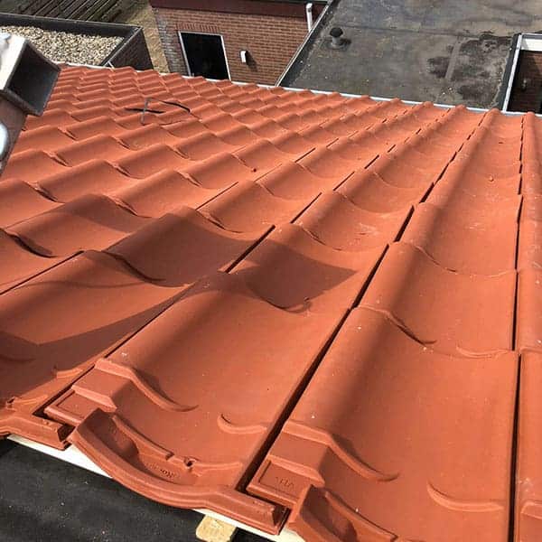 Schuin dak met rode golvende keramische dakpannen op stedelijke woning
