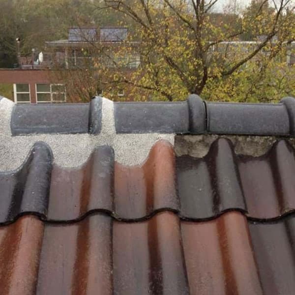 Close-up dakreparatie: mortelafdichting op nokvorsten met rode keramische dakpannen