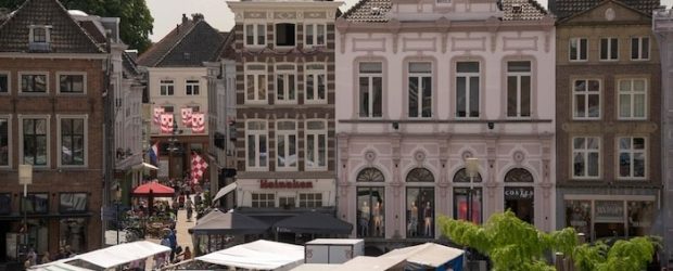 Drukke Nederlandse winkelstraat met marktstalletjes, sfeervolle terrassen en historische middeleeuwse gevels