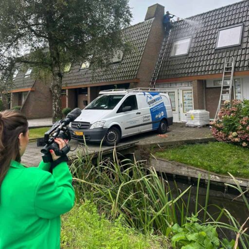 Monteur voert dakreiniging uit met hogedrukspuit, Eigenhuis bestelwagen op oprit