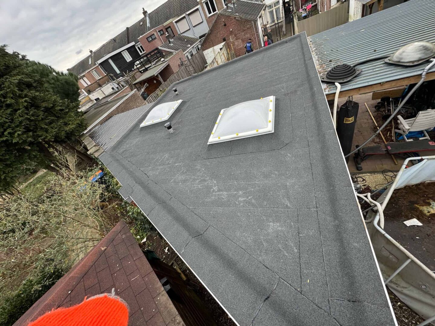Nieuw plat dak met bitumen en twee lichtkoepels op achterbouw