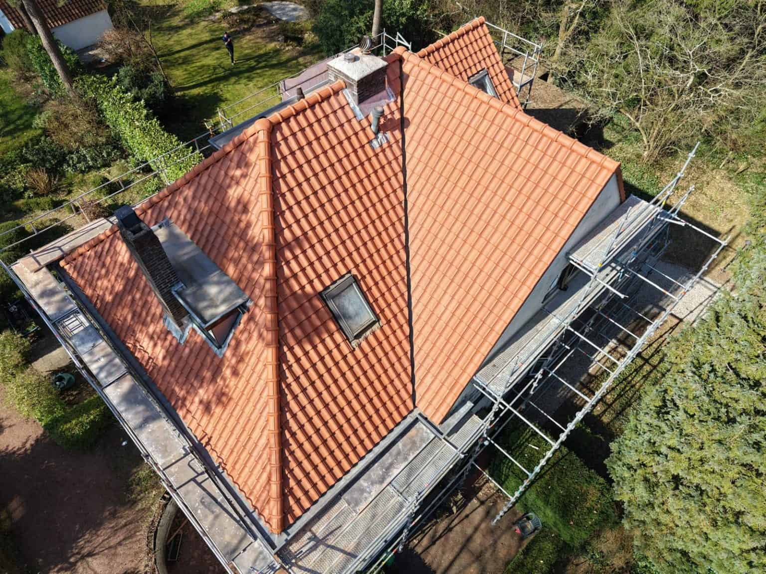 Luchtfoto van huis met nieuwe oranje dakpannen en omringende steigers