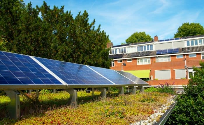 Zonnepanelen op groen sedumdak van modern woongebouw, duurzame energie in stedelijke omgeving